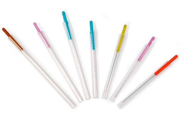 Rainbow assortment of acupuncture needles in guide tubes with multi-colored handles.